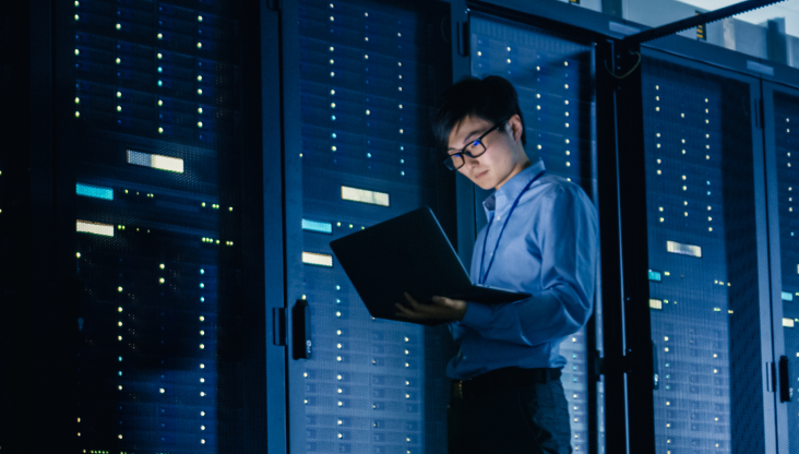 Employee looking at laptop in a data center warehouse