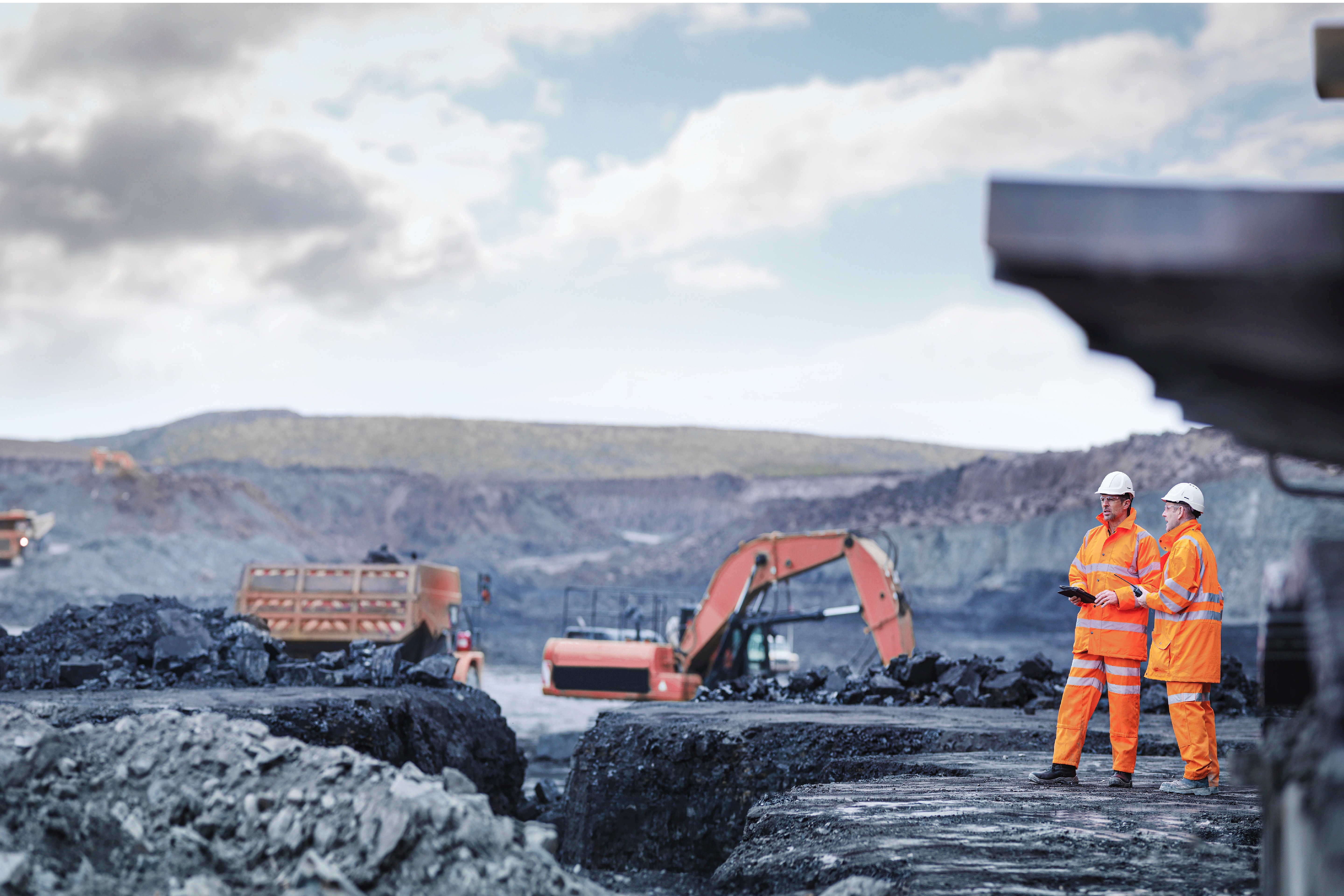 Miners stand on site with tablets.