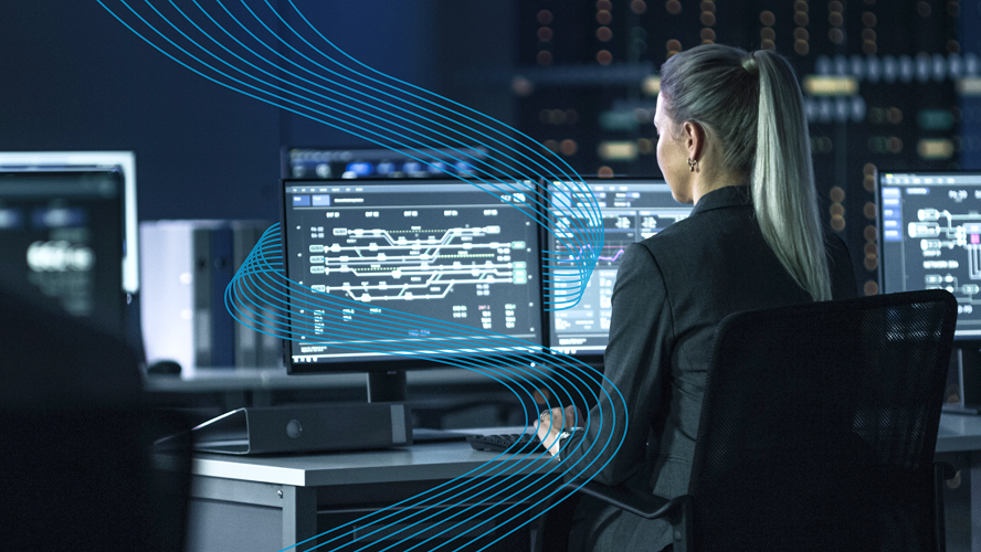 Employee sitting at her desk and working on two large monitors