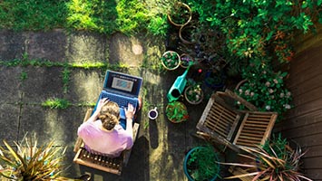 Person working on laptop in garden setting