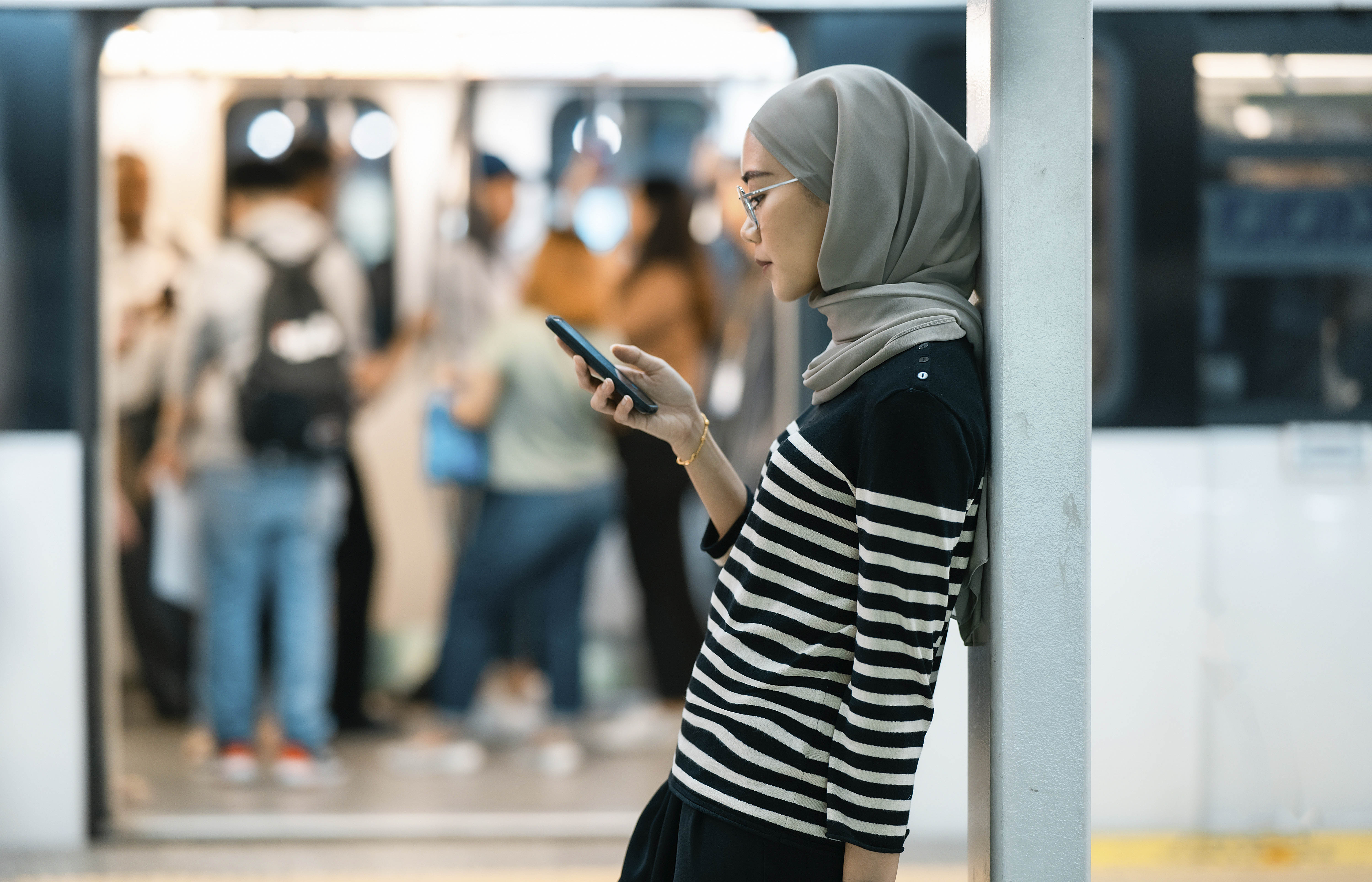 Woman is on phone outside of an open subway car.